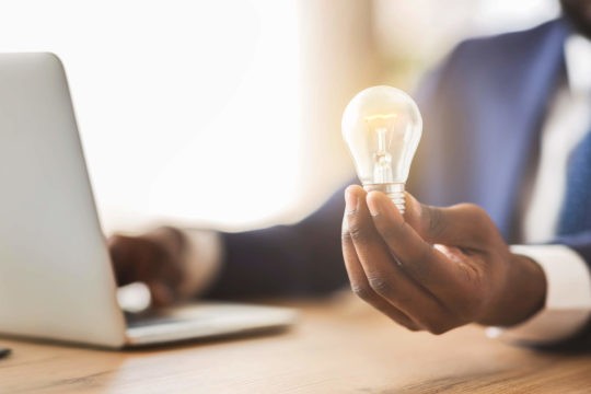 Business man in front of a laptop holding a light bulb