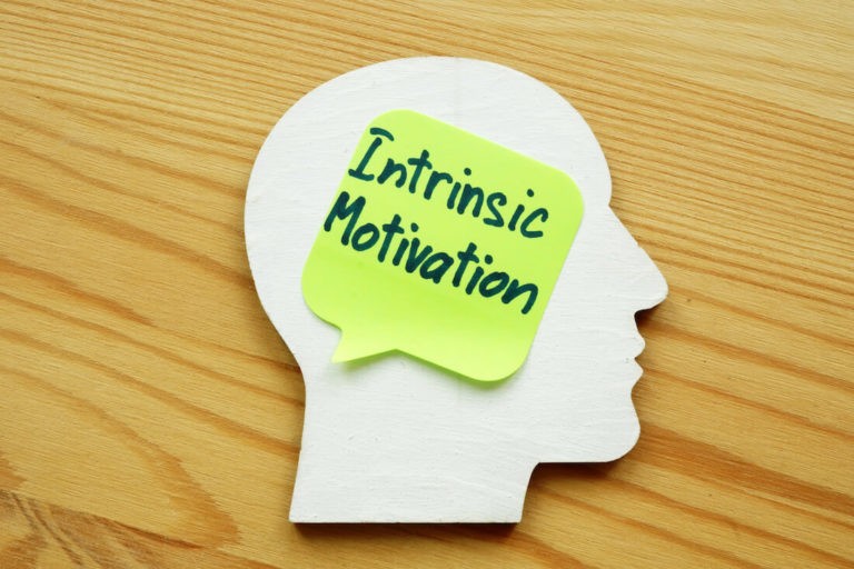 Sticky note that reads 'Intrinsic Motivation' stuck to a paper cut out of a head