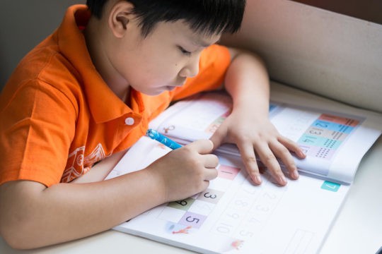 Young boy working on numbers worksheet at home