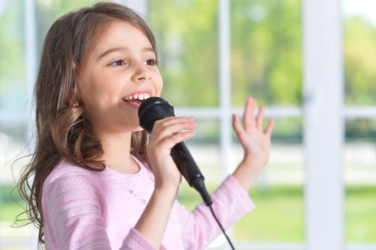Young smiling girl singing into a microphone