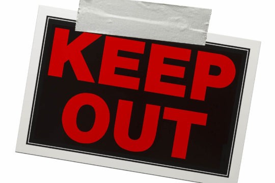 A red and black ‘Keep Out’ sign with duct tape holding it up