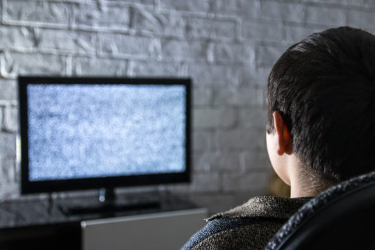 Young boy watching a TV that has static on the screen