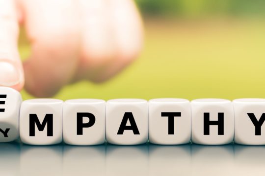 Hand turns dice and changes the word “sympathy” to “empathy.”