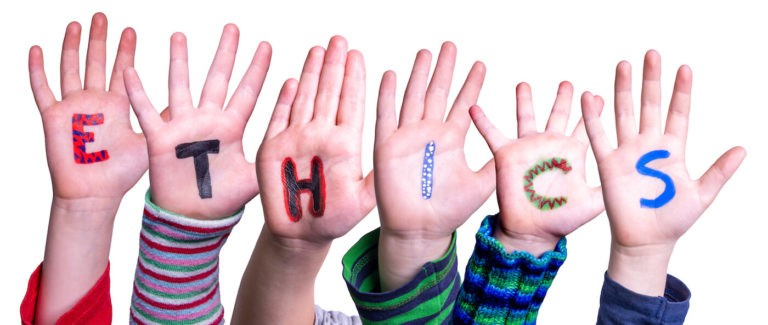 Child hands build the word “ethics” with each letter written on their palms.