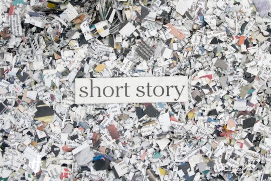 Book confetti shown from above with the text “short story” written over it.