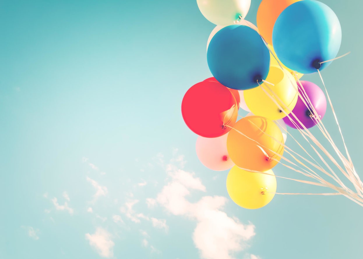 A group of colorful balloons floating up in the sky