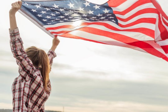 Girl outside holding up an American flag